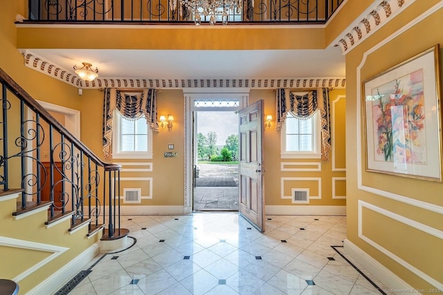foyer with plenty of natural light, a chandelier, stairway, and inlaid floor details