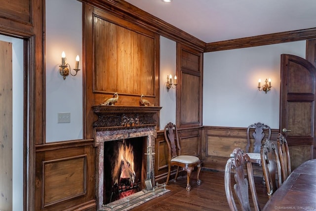 living area featuring a wainscoted wall, a fireplace, dark wood-style flooring, and crown molding