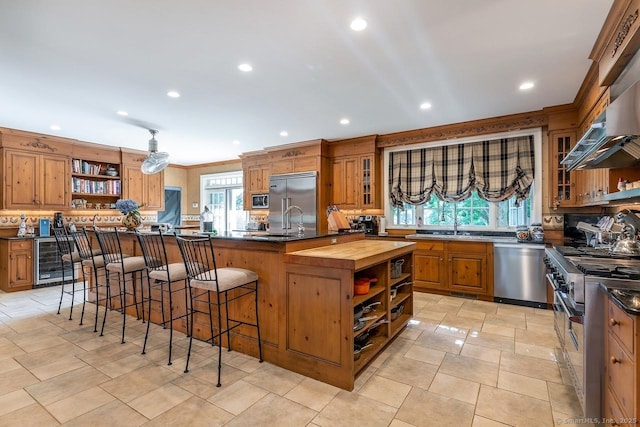 kitchen featuring open shelves, high end appliances, butcher block countertops, wine cooler, and brown cabinets