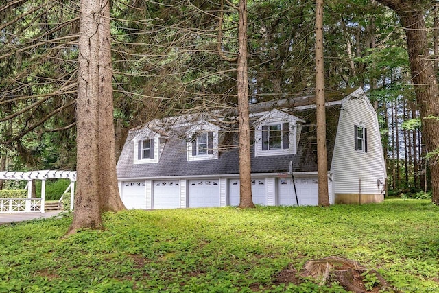 view of front facade with a gambrel roof, a garage, and a shingled roof