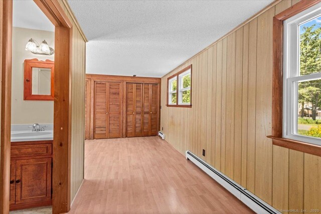 45 Canton Rd, Granby, CT 06035 - corridor featuring baseboard heating, light wood-style flooring, wooden walls, and a textured ceiling