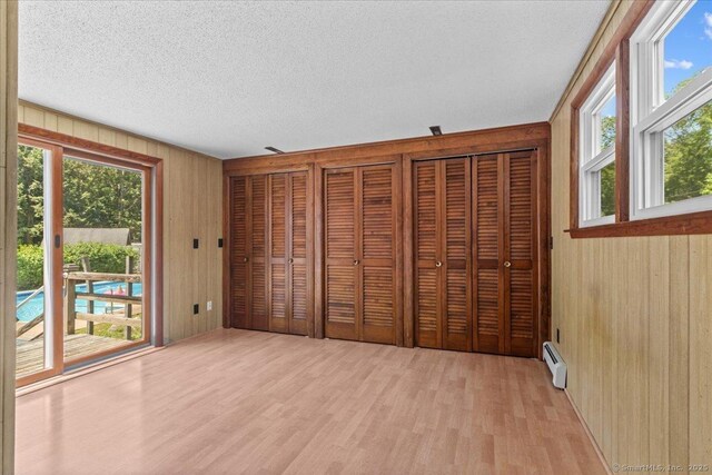 45 Canton Rd, Granby, CT 06035 - unfurnished bedroom with wood walls, access to exterior, baseboard heating, light wood-type flooring, and multiple windows