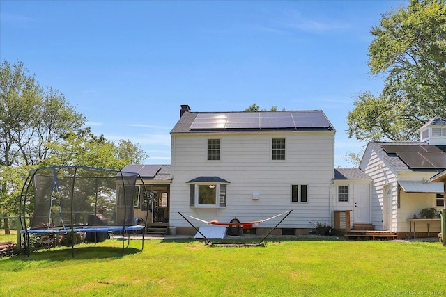 80 Bread And Milk St, Coventry, CT 06238 - back of house with entry steps, a trampoline, roof mounted solar panels, and a lawn