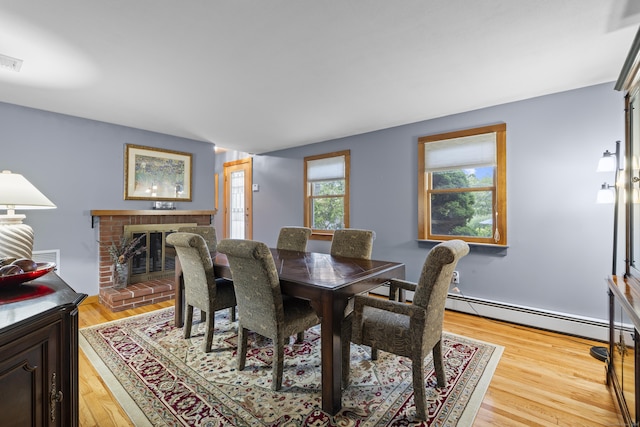 34 Joyce St, Guilford, CT 06437 - dining space featuring light wood finished floors, a brick fireplace, and a baseboard heating unit