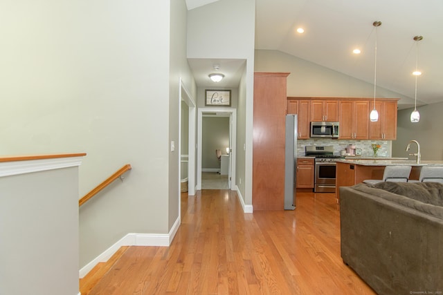 40 Airport Rd, Killingly, CT 06239 - kitchen with appliances with stainless steel finishes, light wood finished floors, brown cabinetry, pendant lighting, and backsplash