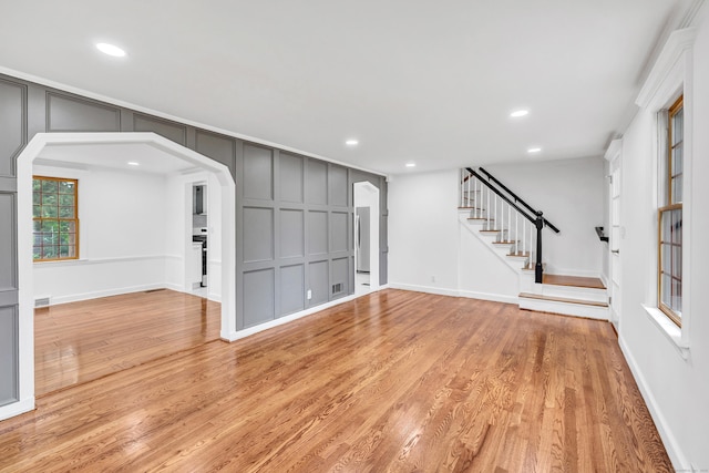 162 Sheppard St, Stratford, CT 06614 - unfurnished living room featuring a decorative wall, recessed lighting, light wood-style floors, arched walkways, and stairs