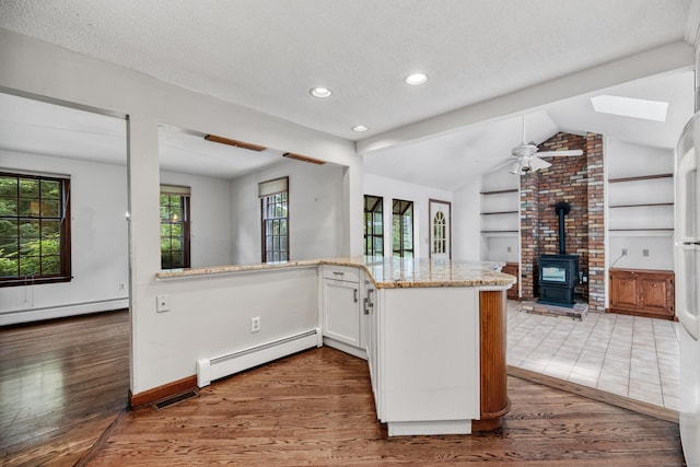 70 Brighton Rd, Hebron, CT 06248 - kitchen with a baseboard radiator, a wood stove, light stone countertops, wood finished floors, and lofted ceiling
