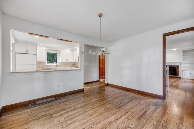 70 Brighton Rd, Hebron, CT 06248 - unfurnished living room featuring wood finished floors, a chandelier, and a fireplace