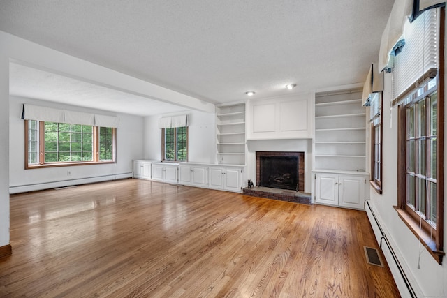 70 Brighton Rd, Hebron, CT 06248 - unfurnished living room featuring a baseboard radiator, light wood finished floors, a fireplace, a baseboard heating unit, and a textured ceiling