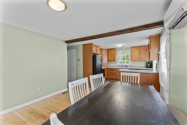64 Iron St, Ledyard, CT 06339 - kitchen with a wall unit AC, light wood-style flooring, light countertops, freestanding refrigerator, and brown cabinetry