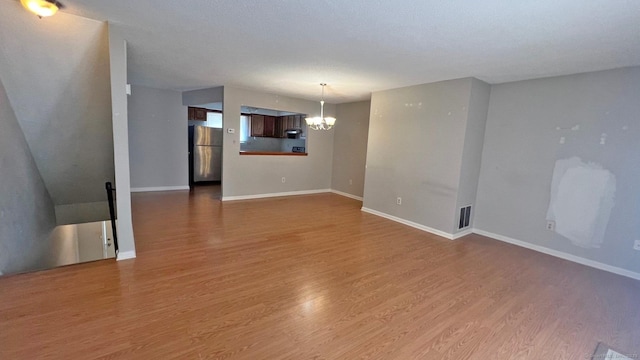 unfurnished living room featuring a chandelier and wood finished floors
