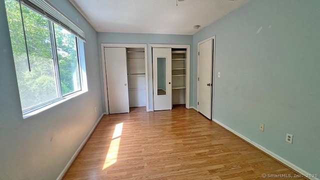 unfurnished bedroom with multiple closets and light wood-type flooring