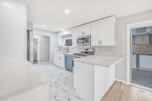 34 2nd Ave, East Haven, CT 06512 - kitchen with appliances with stainless steel finishes, white cabinetry, tasteful backsplash, a peninsula, and recessed lighting