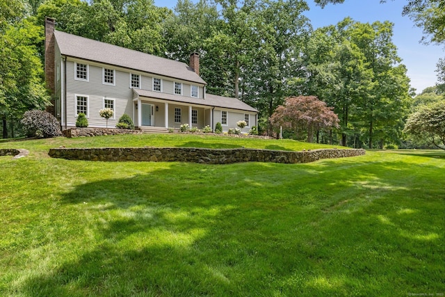 392 Hoyt Farm Rd, New Canaan, CT 06840 - colonial home featuring a chimney, a porch, a front lawn, and view of scattered trees