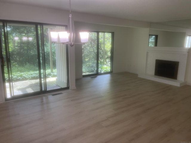 277 Heritage Vlg Unit C, Southbury, CT 06488 - unfurnished living room featuring wood finished floors, a fireplace, and a chandelier