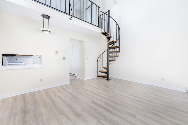 430 Emmett St Apt L, Bristol, CT 06010 - unfurnished living room with wood finished floors, a baseboard radiator, stairs, and a towering ceiling