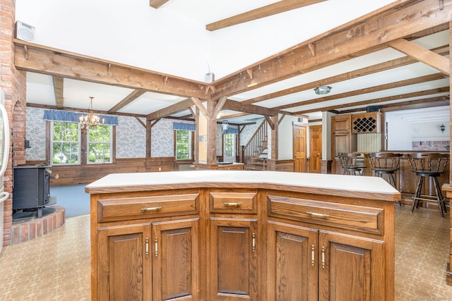 934 Jerome Ave, Bristol, CT 06010 - kitchen with beam ceiling, brown cabinetry, wainscoting, plenty of natural light, and a wood stove