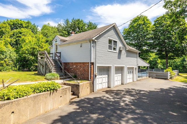 934 Jerome Ave, Bristol, CT 06010 - view of home's exterior featuring stairway, asphalt driveway, a garage, brick siding, and a shingled roof