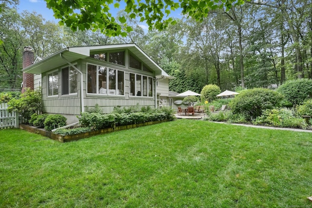 70 Bayne St, Norwalk, CT 06851 - view of property exterior with a chimney, a lawn, a patio area, and a sunroom