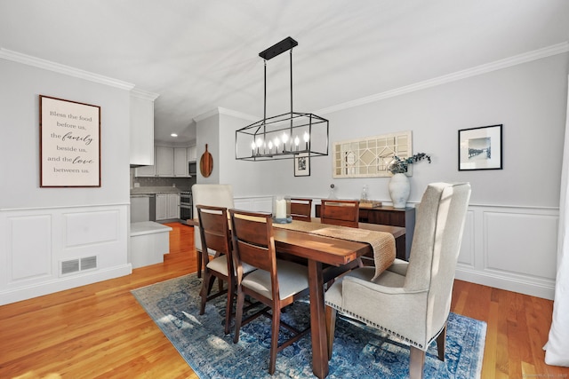 30 Poppy Ln, East Lyme, CT 06333 - dining space featuring ornamental molding, light wood-type flooring, a decorative wall, a chandelier, and wainscoting