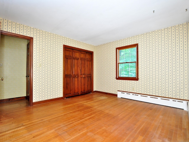 3 Carriage Dr, Canton, CT 06019 - unfurnished bedroom featuring baseboard heating, light wood finished floors, wallpapered walls, and a closet