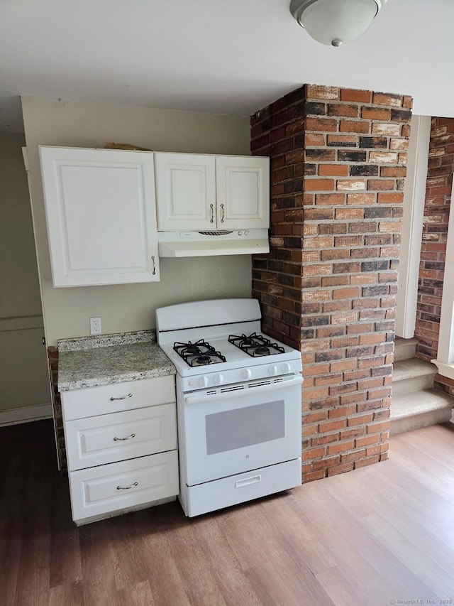 181 Plank Rd, Waterbury, CT 06705 - kitchen featuring gas range gas stove, under cabinet range hood, dark wood-style floors, white cabinetry, and brick wall