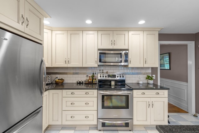 19 Buttercup Ln, Shelton, CT 06484 - kitchen featuring appliances with stainless steel finishes, cream cabinetry, dark countertops, a wainscoted wall, and recessed lighting