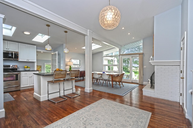 23 Briarwood Dr, Old Saybrook, CT 06475 - kitchen featuring stainless steel appliances, dark countertops, white cabinets, dark wood finished floors, and a kitchen breakfast bar