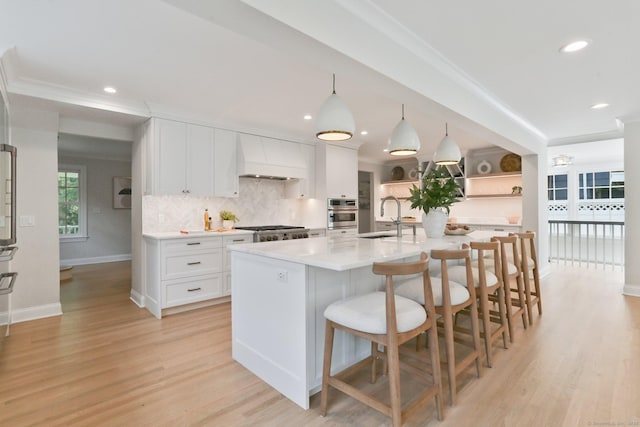 36 Hendrie Ave, Greenwich, CT 06878 - kitchen featuring white cabinets, decorative backsplash, light wood-type flooring, open shelves, and a breakfast bar