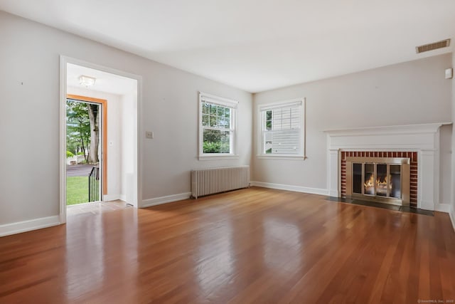 22 Brundage St, Stamford, CT 06907 - unfurnished living room featuring radiator heating unit, healthy amount of natural light, wood finished floors, and a fireplace
