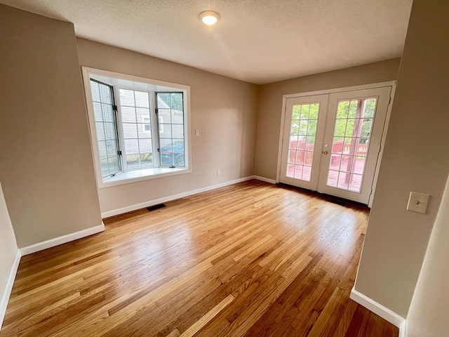 212 Clement Rd, East Hartford, CT 06118 - spare room with light wood-type flooring, french doors, and a textured ceiling