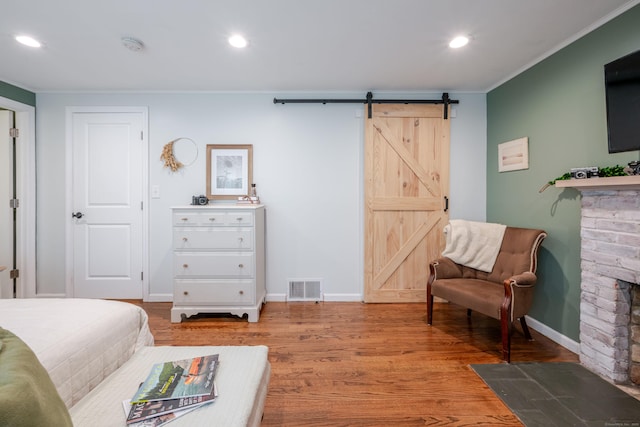 81 Burwell Rd, New Hartford, CT 06057 - bedroom featuring a barn door, crown molding, wood finished floors, a brick fireplace, and recessed lighting
