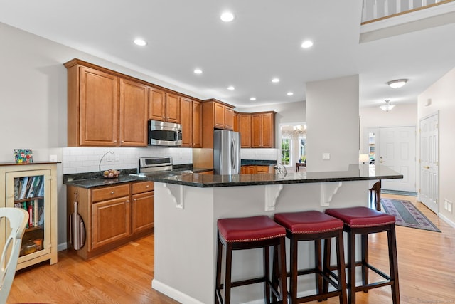 25 Quarry Ln Unit 25, Berlin, CT 06037 - kitchen with stainless steel appliances, light wood finished floors, a breakfast bar, brown cabinetry, and recessed lighting