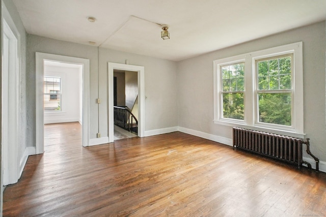 67 Whiting St, New Britain, CT 06051 - empty room featuring radiator heating unit, plenty of natural light, wood finished floors, and a smoke detector