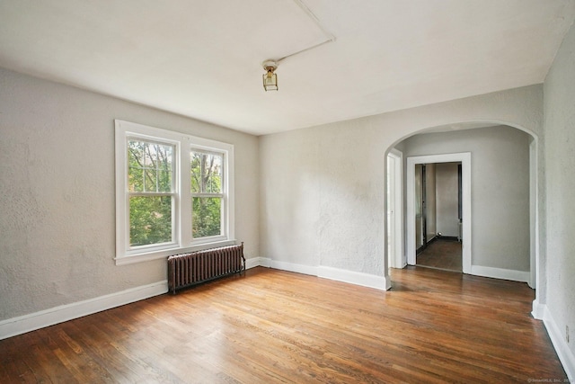 67 Whiting St, New Britain, CT 06051 - empty room featuring radiator heating unit, arched walkways, wood finished floors, and a textured wall