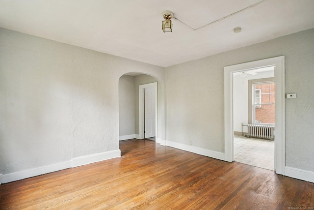 67 Whiting St, New Britain, CT 06051 - unfurnished room with radiator, arched walkways, wood finished floors, a smoke detector, and a textured wall