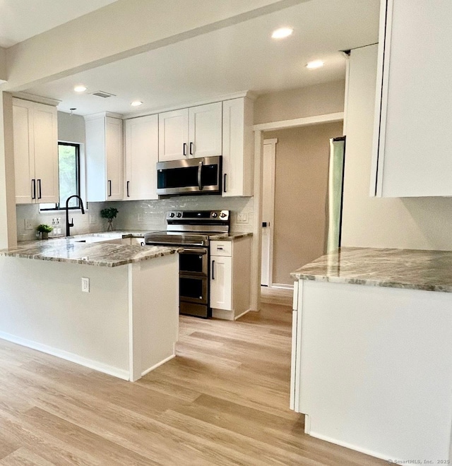 900 Heritage Vlg Unit B, Southbury, CT 06488 - kitchen featuring appliances with stainless steel finishes, white cabinetry, light wood-type flooring, tasteful backsplash, and light stone counters