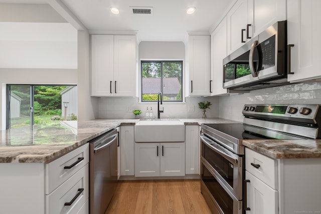 900 Heritage Vlg Unit B, Southbury, CT 06488 - kitchen featuring stainless steel appliances, a peninsula, light wood-style flooring, light stone counters, and tasteful backsplash