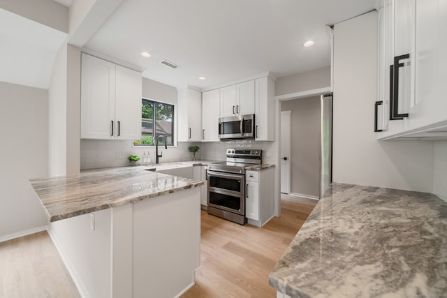 900 Heritage Vlg Unit B, Southbury, CT 06488 - kitchen with appliances with stainless steel finishes, a peninsula, light wood-type flooring, light stone countertops, and recessed lighting