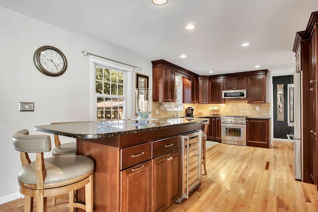9 Anton Ln, Berlin, CT 06037 - kitchen featuring appliances with stainless steel finishes, beverage cooler, decorative backsplash, a breakfast bar, and light wood-type flooring