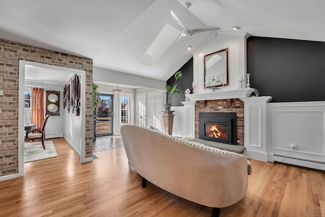 9 Anton Ln, Berlin, CT 06037 - living room featuring lofted ceiling, baseboard heating, light wood-style flooring, a fireplace, and wainscoting