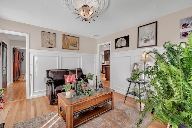 9 Anton Ln, Berlin, CT 06037 - living room with a chandelier, a wainscoted wall, a decorative wall, and light wood-style flooring