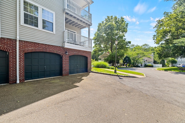 306 Hadley Dr Unit 306, Trumbull, CT 06611 - view of home's exterior featuring an attached garage, brick siding, a balcony, and driveway