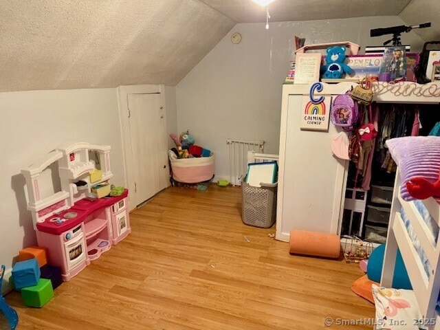 72 Stewart St, Bristol, CT 06010 - game room featuring radiator, wood finished floors, lofted ceiling, and a textured ceiling