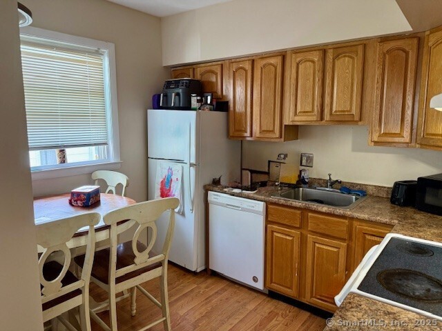 72 Stewart St, Bristol, CT 06010 - kitchen with white appliances, light wood-type flooring, and brown cabinetry