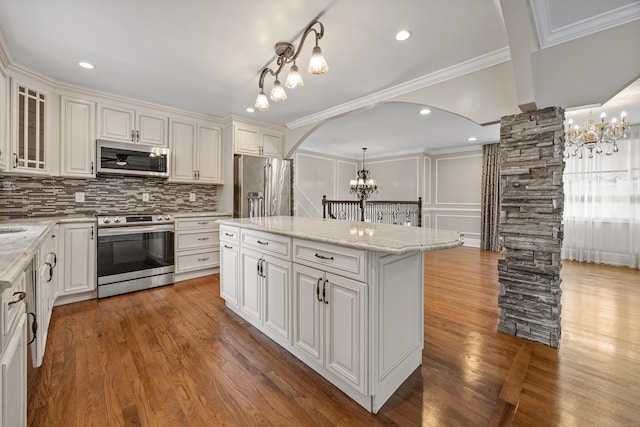 90 Haddad Rd, Waterbury, CT 06708 - kitchen with appliances with stainless steel finishes, a chandelier, arched walkways, ornate columns, and a kitchen island