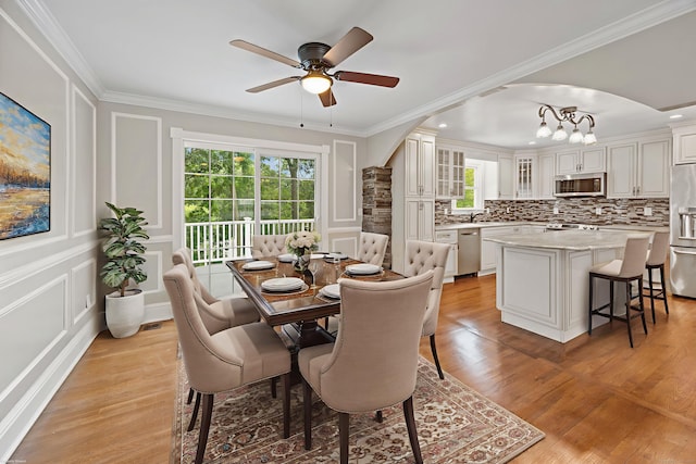 90 Haddad Rd, Waterbury, CT 06708 - dining area featuring ceiling fan, light wood-style flooring, ornamental molding, a decorative wall, and a chandelier