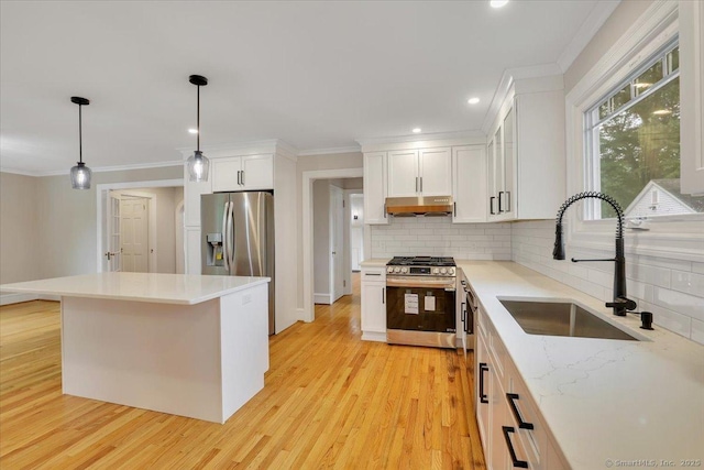 502 Adams St, Manchester, CT 06040 - kitchen with appliances with stainless steel finishes, under cabinet range hood, ornamental molding, tasteful backsplash, and light wood-style flooring