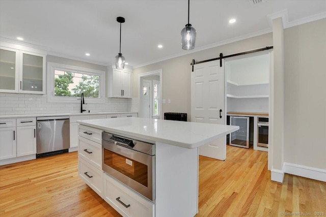 502 Adams St, Manchester, CT 06040 - kitchen with appliances with stainless steel finishes, a barn door, crown molding, decorative backsplash, and wine cooler