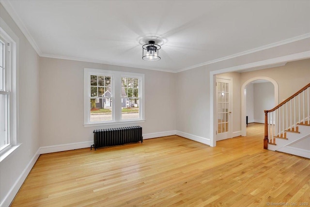 502 Adams St, Manchester, CT 06040 - empty room featuring radiator heating unit, healthy amount of natural light, arched walkways, light wood finished floors, and ornamental molding